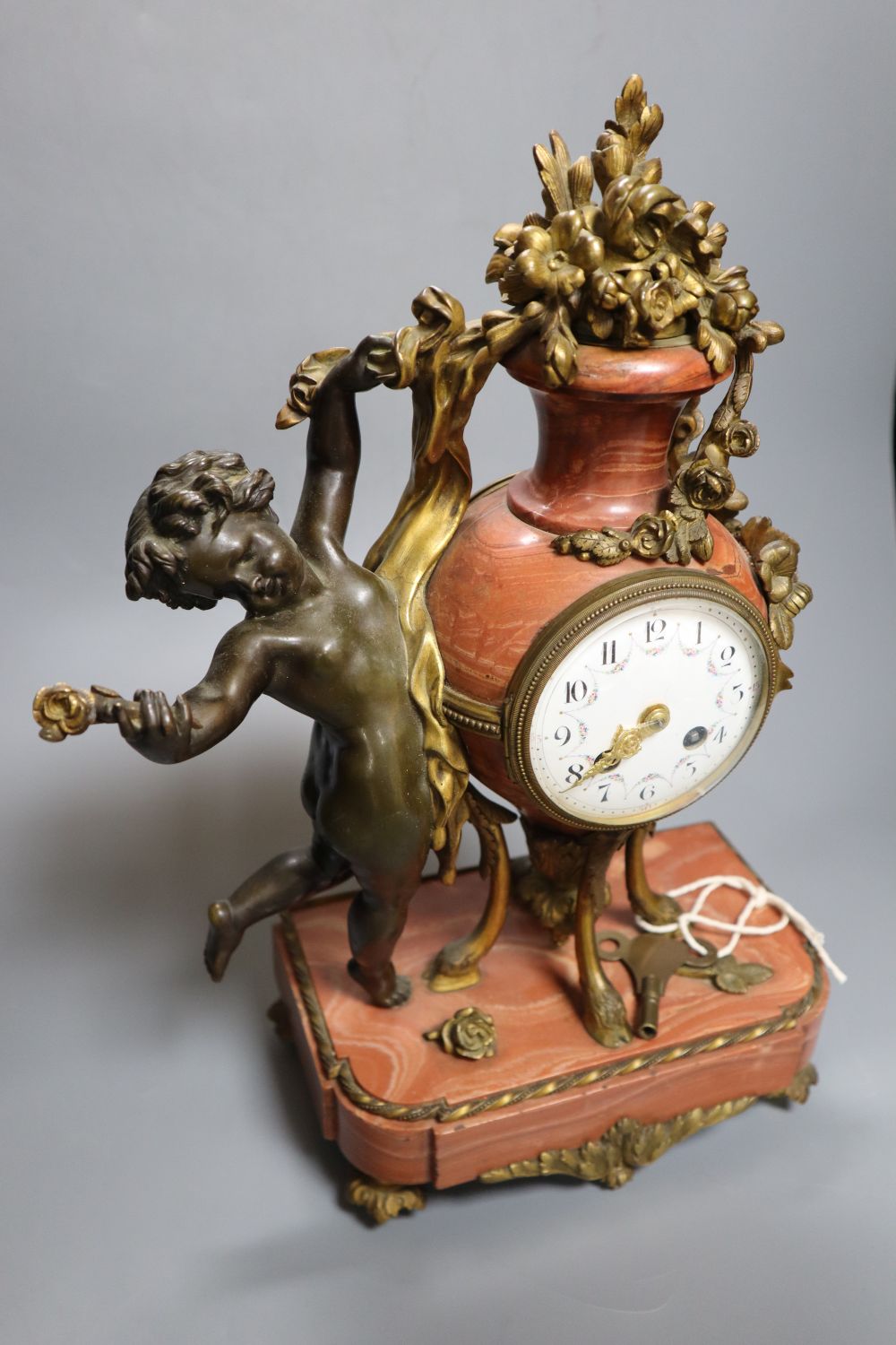 A 19th century French ormolu mounted rouge marble mantel clock, cast with putti, height 36cm